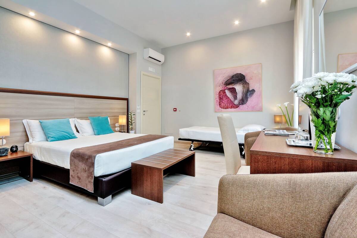 A modern hotel room with a large bed, bedside tables, a desk, and a chair.