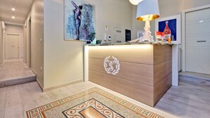 A modern reception area with a wooden counter, a large painting, and a decorative lamp. - Relais Servio Tullio (Rome)