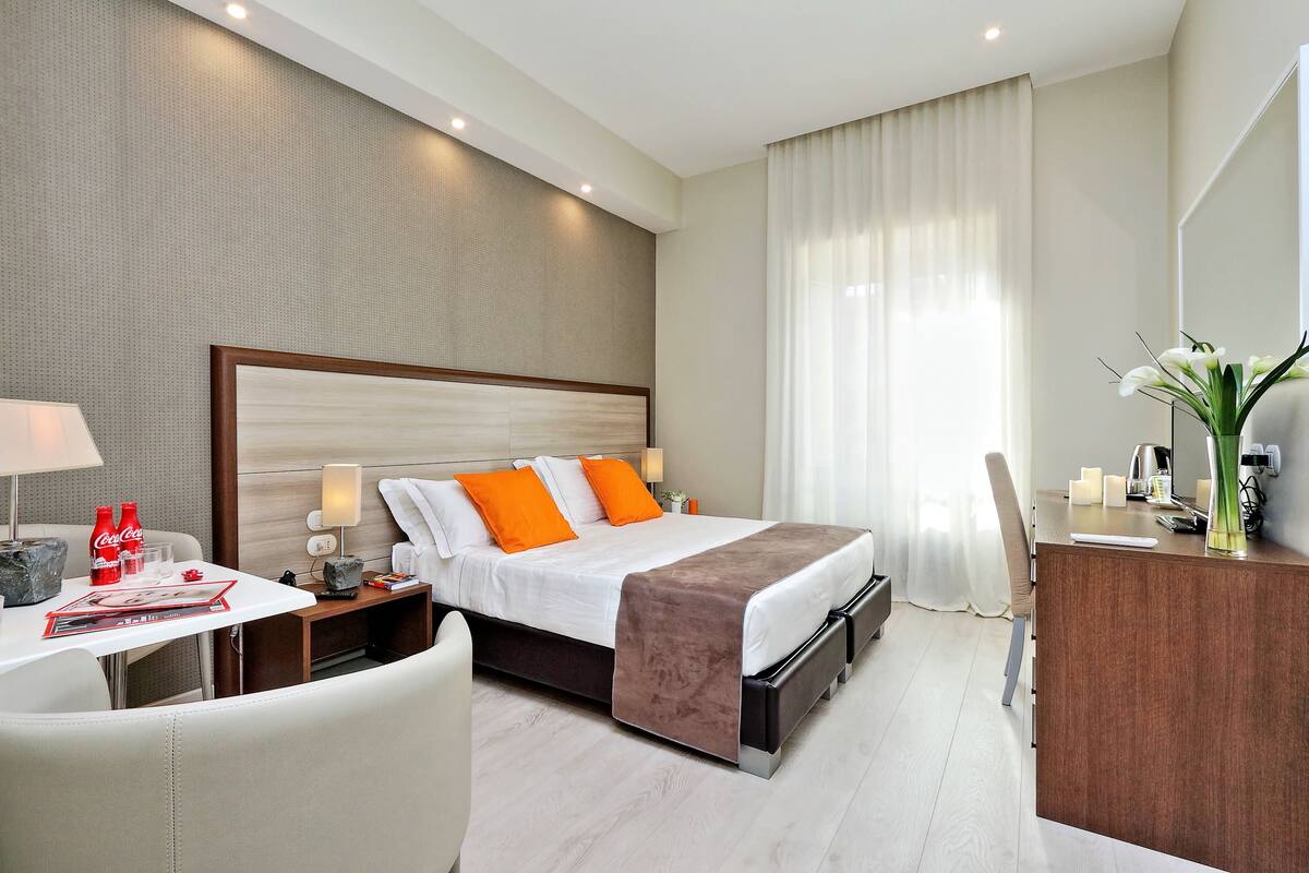 A modern hotel room with a large bed, a desk, and a chair.