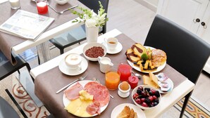 A breakfast table with various food items, a newspaper, and a vase with flowers. - Relais Servio Tullio (Rome)