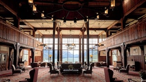 Un hall d’entrée spacieux, doté d’une grande fenêtre offrant une vue sur les montagnes, de lambris en bois et d’un tapis à motifs.