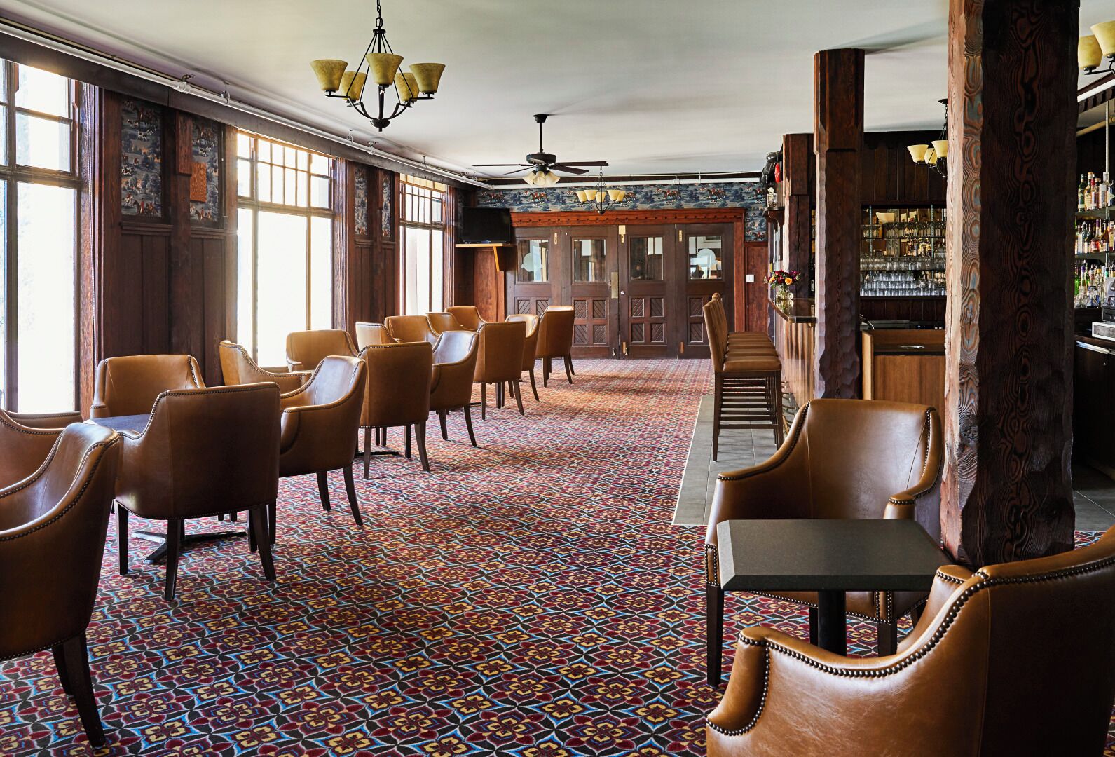 Een hotelhal met een kamerbreed tapijt, lederen stoelen, een bar en een groot raam.