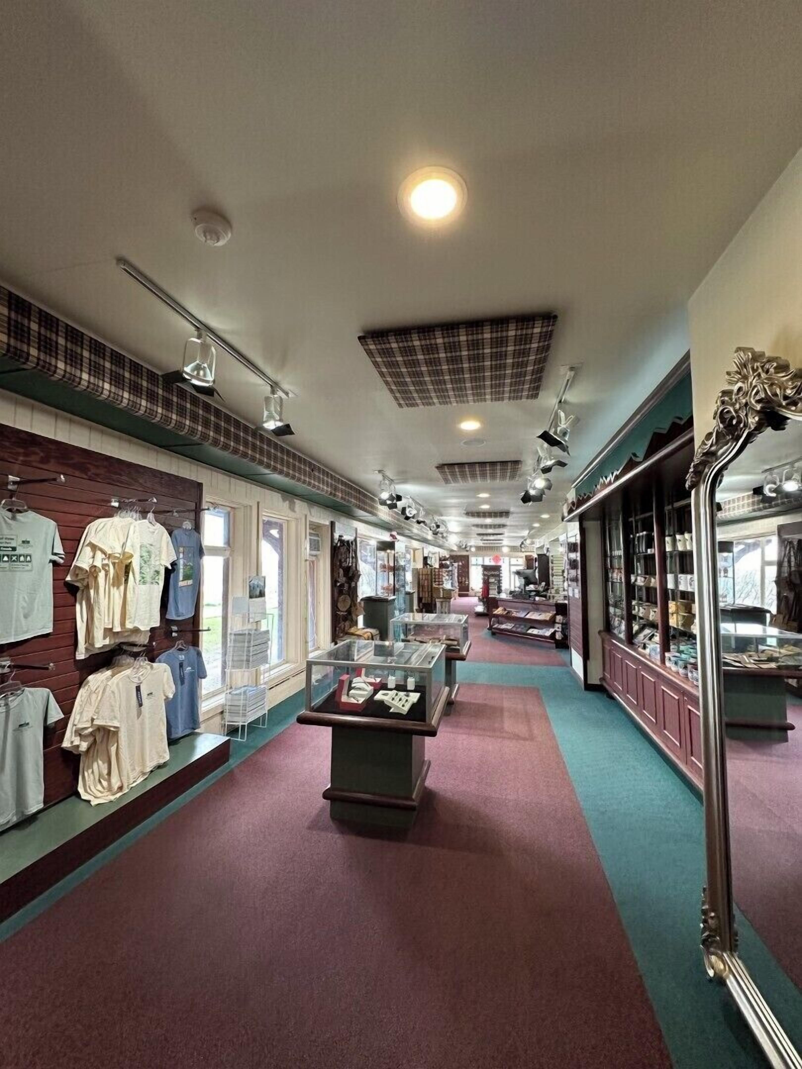 A clothing store with racks of shirts, display cases, and a checkered ceiling.