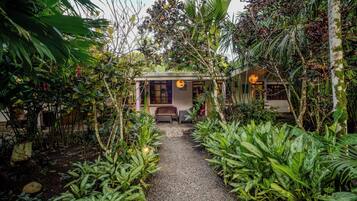 A pathway leading to a building with a traditional design, surrounded by lush greenery and tropical plants.