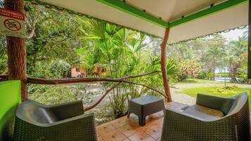 An outdoor seating area with wicker furniture and a view of a lush garden.