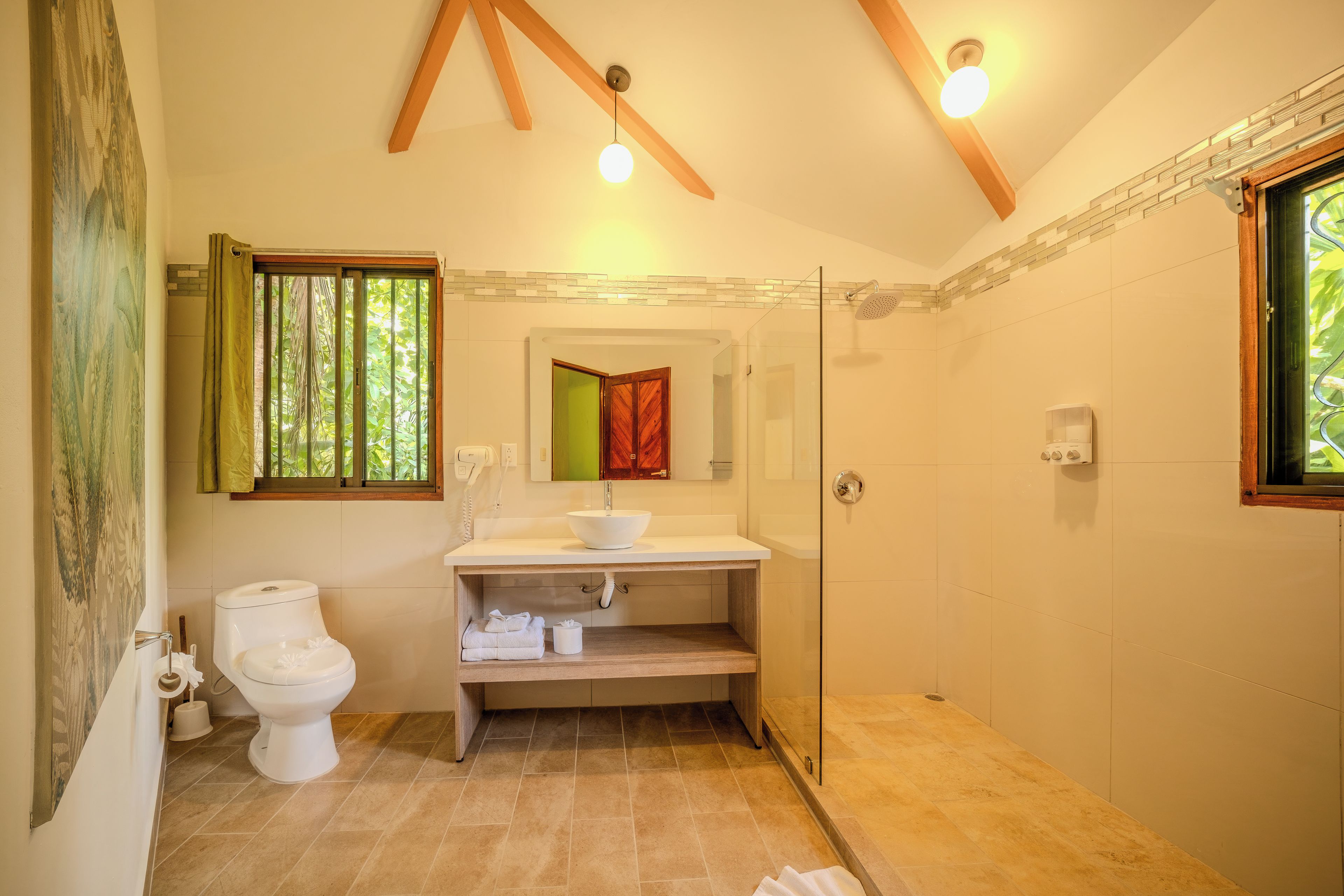 Un baño con inodoro, lavamanos y zona de ducha.