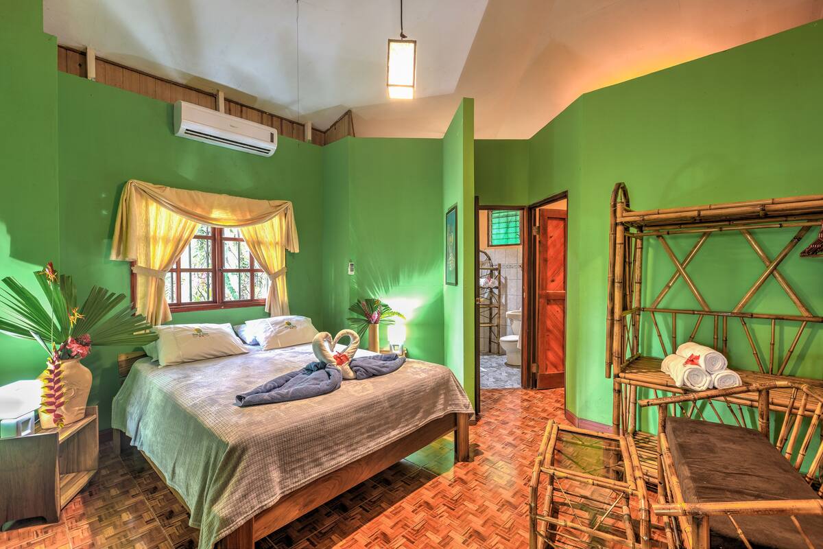 A room with a bed, a window with curtains, a bedside table, and a chair.