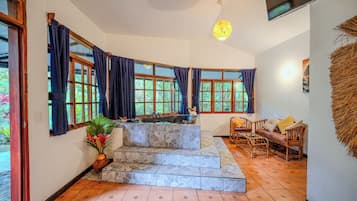 Habitació amb sòl de lloses de pedra, cuina integrada amb un rentatge i zona de seients amb sofà i cadires.