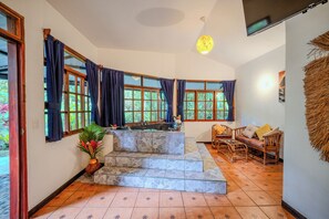 A room with a stone-tiled floor, a built-in kitchen with a sink, and a seating area with a sofa and chairs. - La Diosa Nature Lodge (Cahuita)