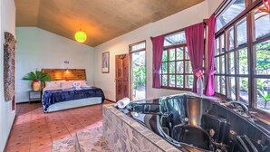 A bedroom with a large bed, a bathtub, and a window with curtains.