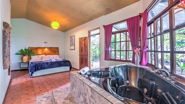 Un dormitorio con una cama grande, una bañera y una ventana con cortinas.