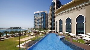 A swimming pool with a view of the sea and high-rise buildings. - Bab Al Qasr Residence (Abu Dhabi)