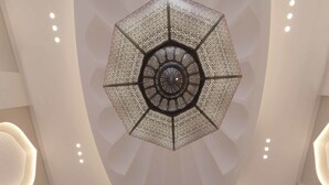 A modern interior with a geometric ceiling design, a central skylight, and a symmetrical staircase. - Bab Al Qasr Residence (Abu Dhabi)