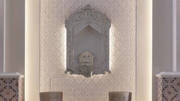 A lobby with two armchairs, a decorative wall, and a small table.