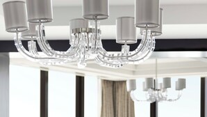 A modern hotel room with a large window, a chandelier, a sofa, a coffee table, and a dining table. - Bab Al Qasr Residence (Abu Dhabi)