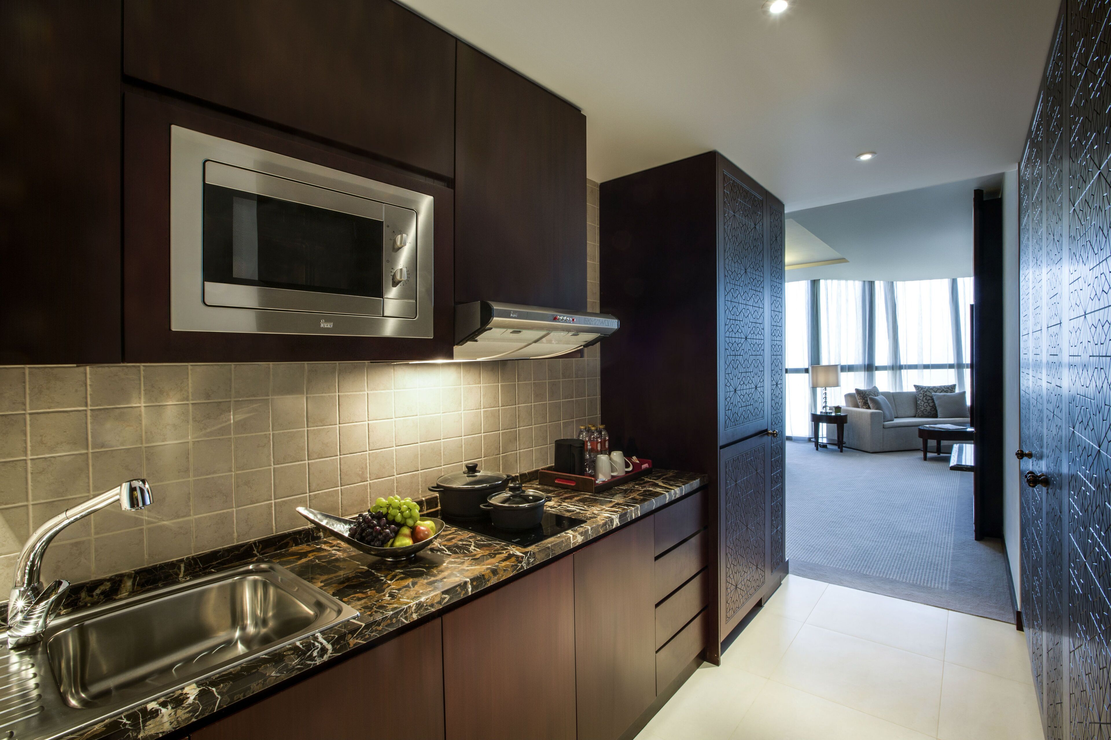 A modern kitchen with dark cabinetry, a stainless steel sink, and a built-in microwave.