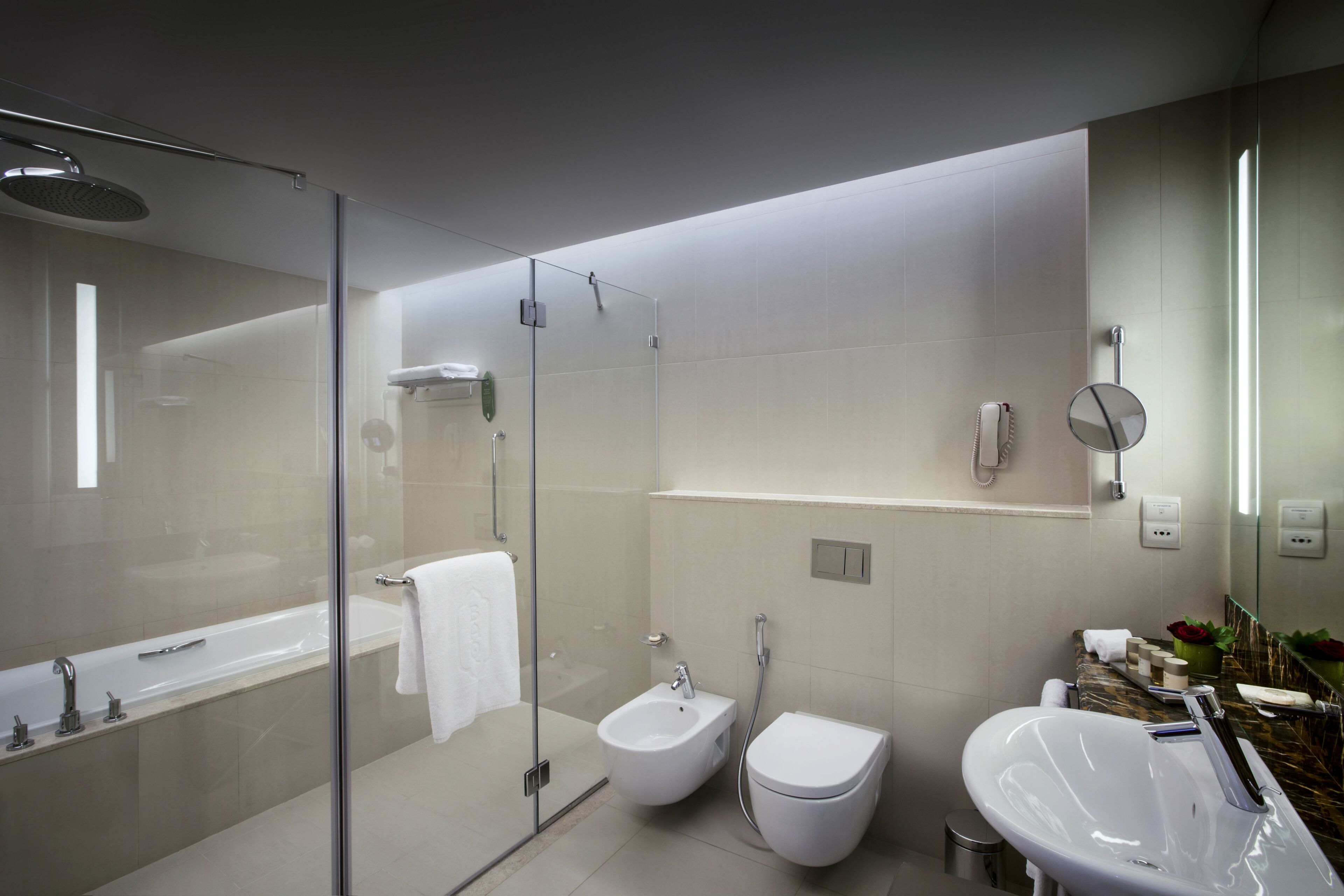 A modern bathroom with a glass-enclosed shower, a bidet, a toilet, and a large sink.