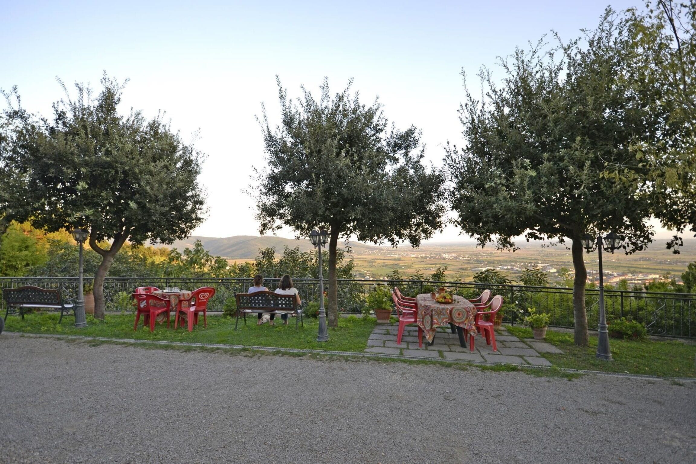 An outdoor seating area with tables and chairs, surrounded by trees and a view of the landscape.
