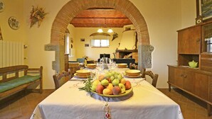Un coin repas avec une table dressée pour quatre personnes, une arche en briques et une cheminée en arrière-plan.