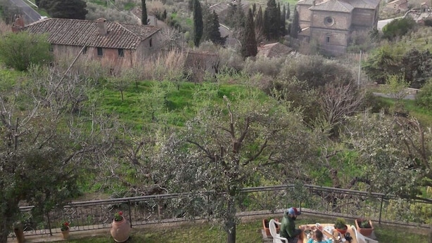 Une terrasse avec une table et des chaises donnant sur un paysage rural, avec une église et des maisons.