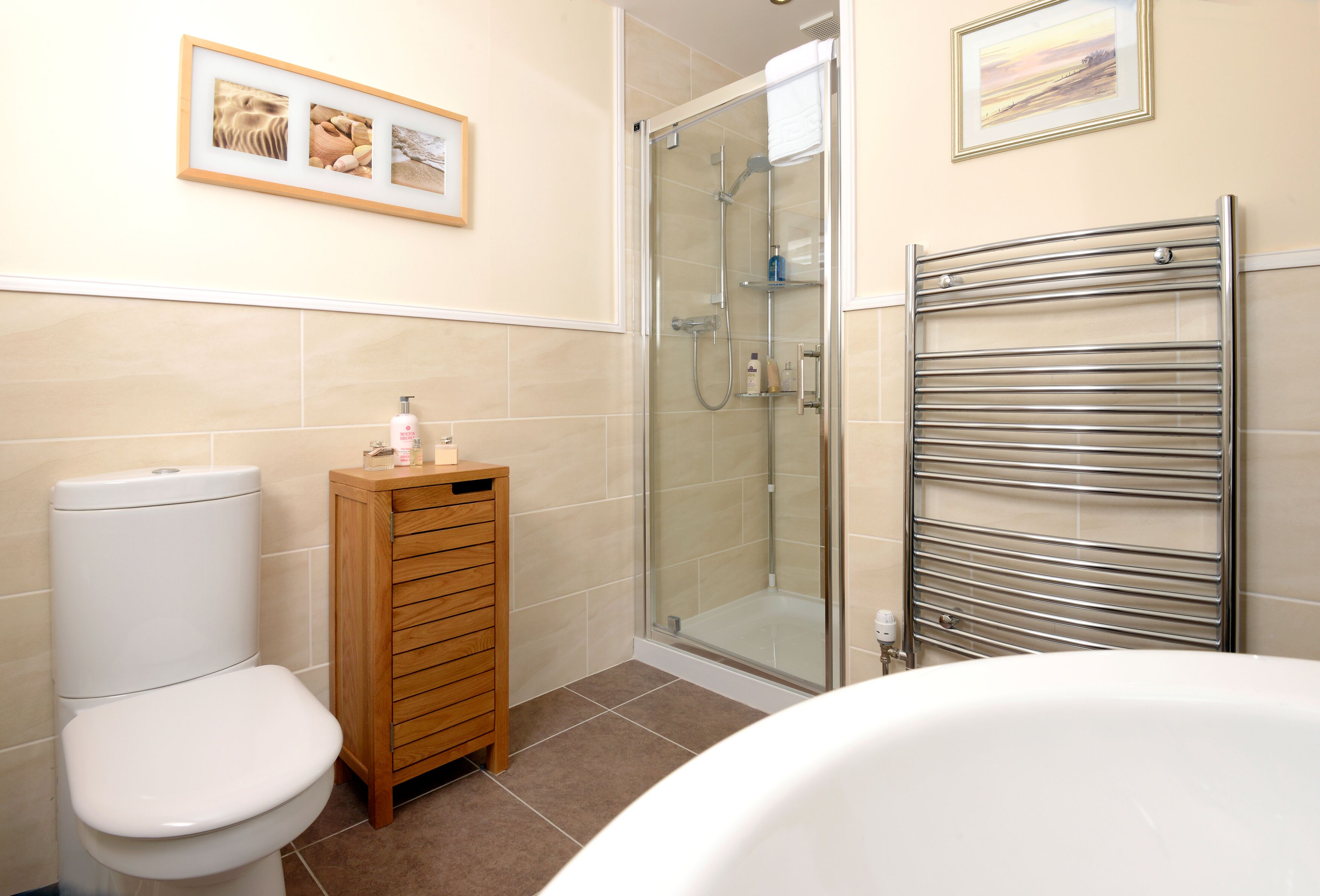 A bathroom with a toilet, a wooden cabinet, a glass shower enclosure, and a bathtub.