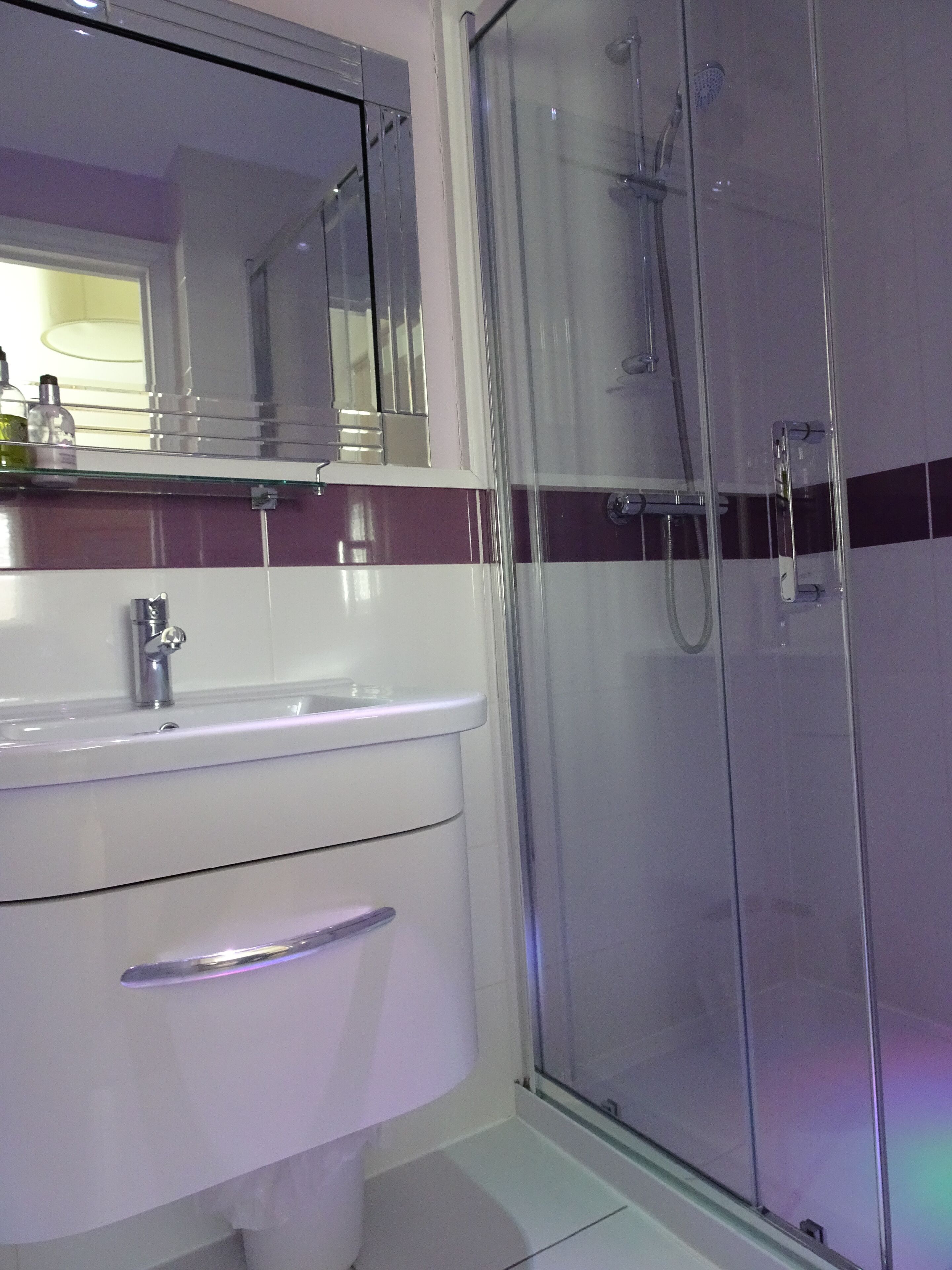 A modern bathroom with a glass shower enclosure, a white sink, and a mirror above the sink.