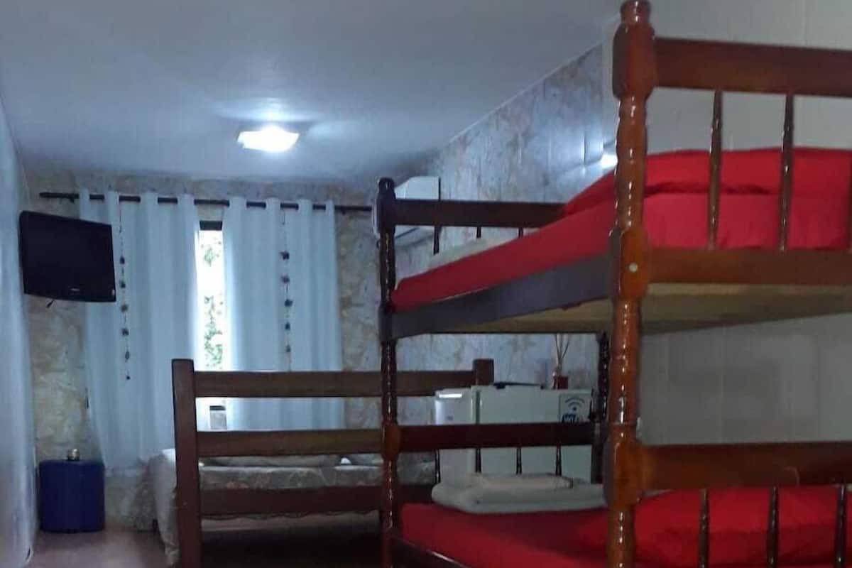 A room with a wooden bunk bed, a small table, and a television on the wall.