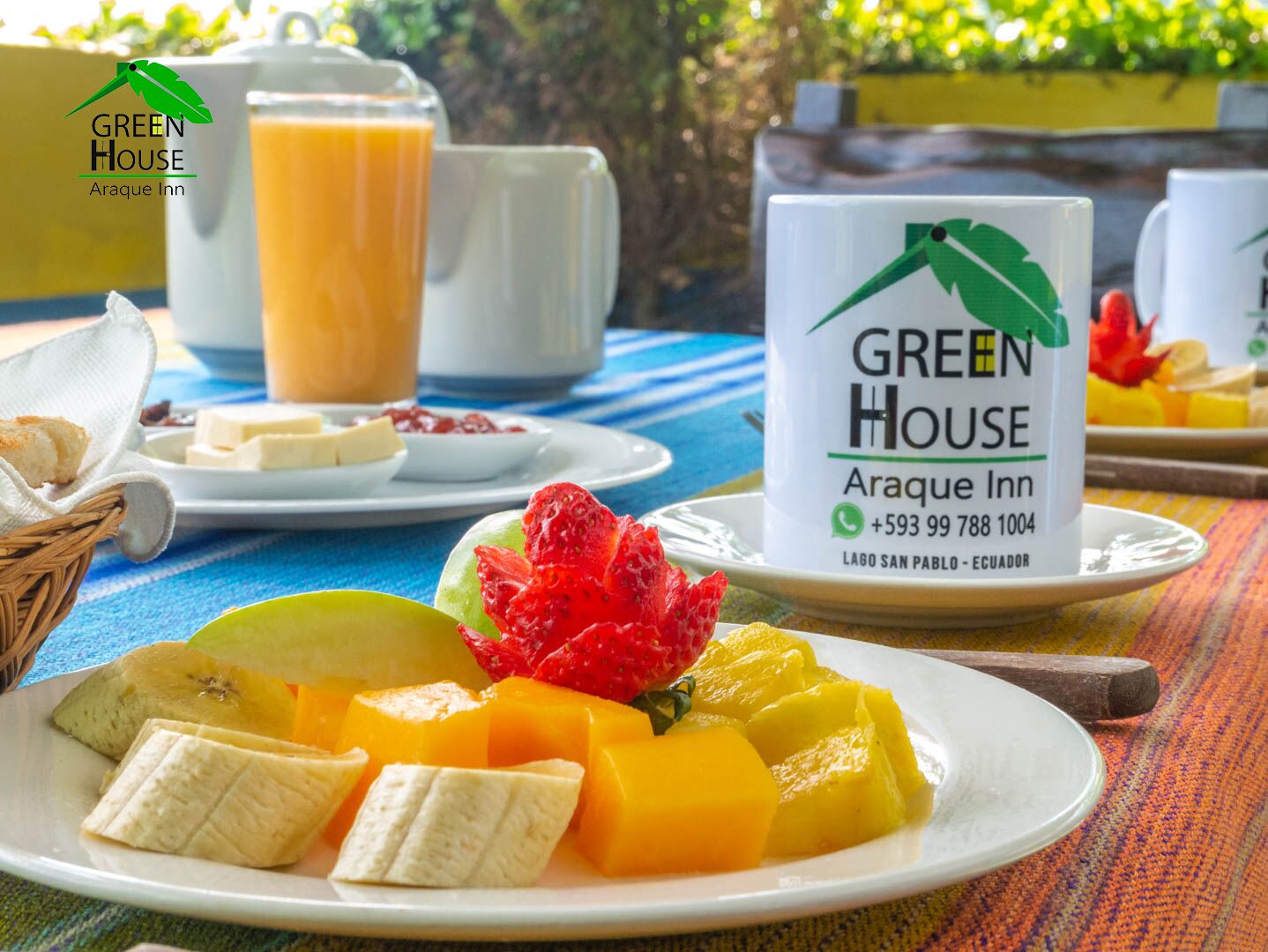Een ontbijttafel met fruit, een koffiekop en een bord met de naam Green House Arareque Inn.