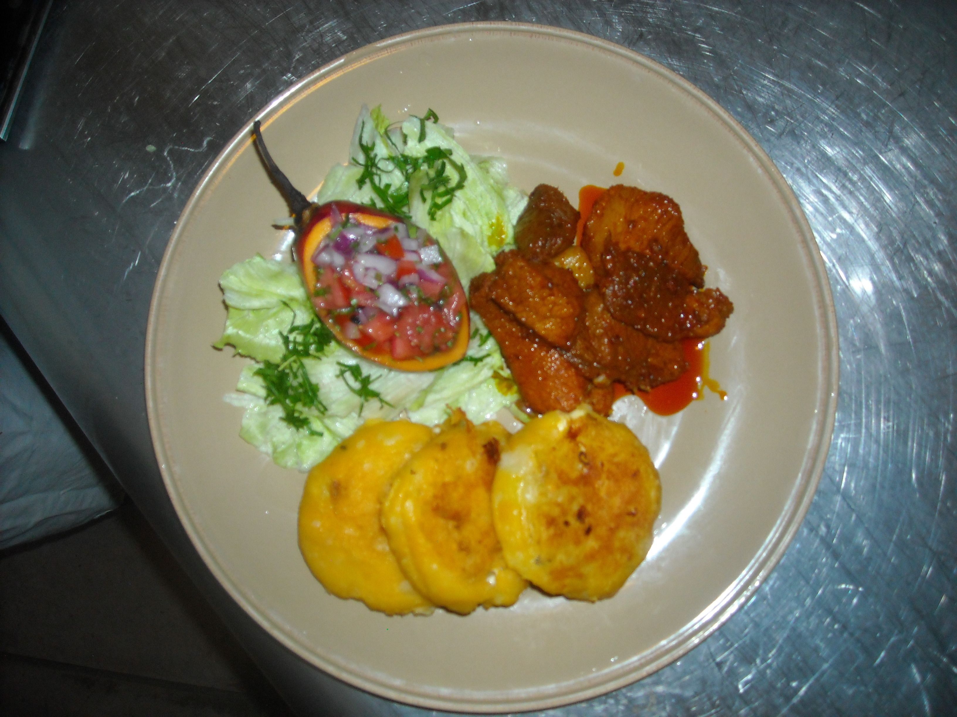 Een bord met een salade, gegrild vlees en gebakken plantains.