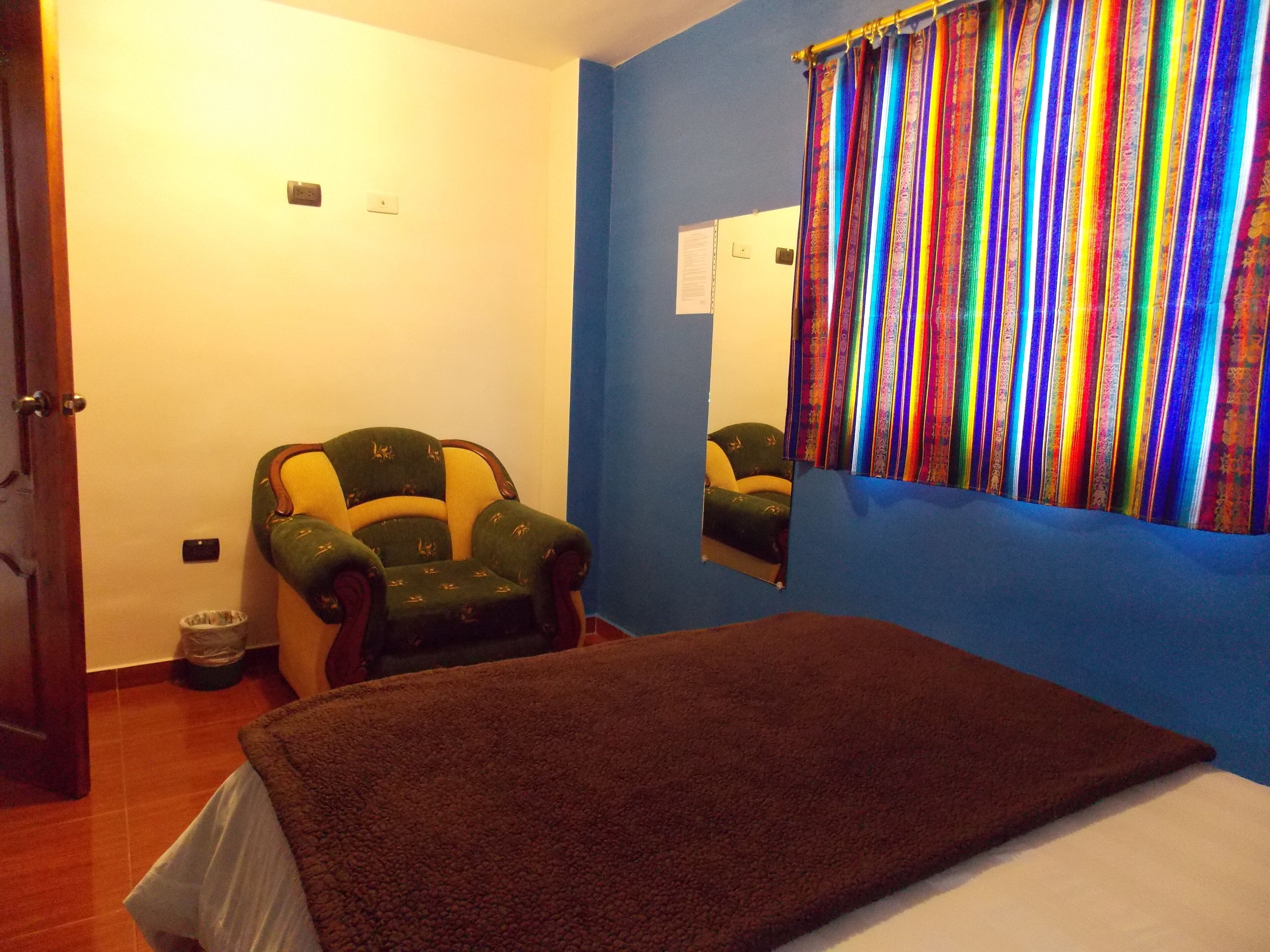 Una habitación con una cama, un sillón de masaje, una pared azul y un espejo.