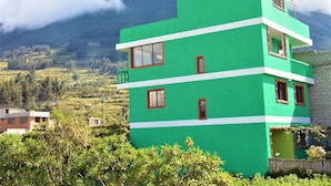 A multi-story building with a green facade, multiple windows, and a balcony. - Green House Araque Inn (San Pablo del Lago)