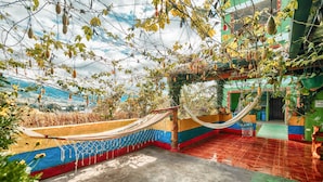 A hammock suspended between colorful walls, a concrete floor, and a view of a distant landscape. - Green House Araque Inn (San Pablo del Lago)
