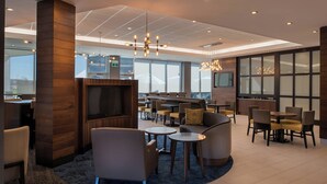 A modern hotel lobby with a seating area, a television, and a bar. - TownePlace Suites by Marriott Saskatoon (Saskatoon)