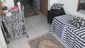 Una habitación con ropa de cama a rayas, una mesita con mantel negro y una alfombra estampada.