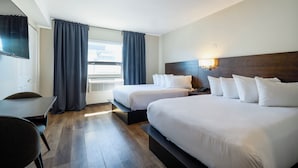 Een hotelkamer met twee bedden, een bureau, een stoel, een televisie en een raam met gordijnen.