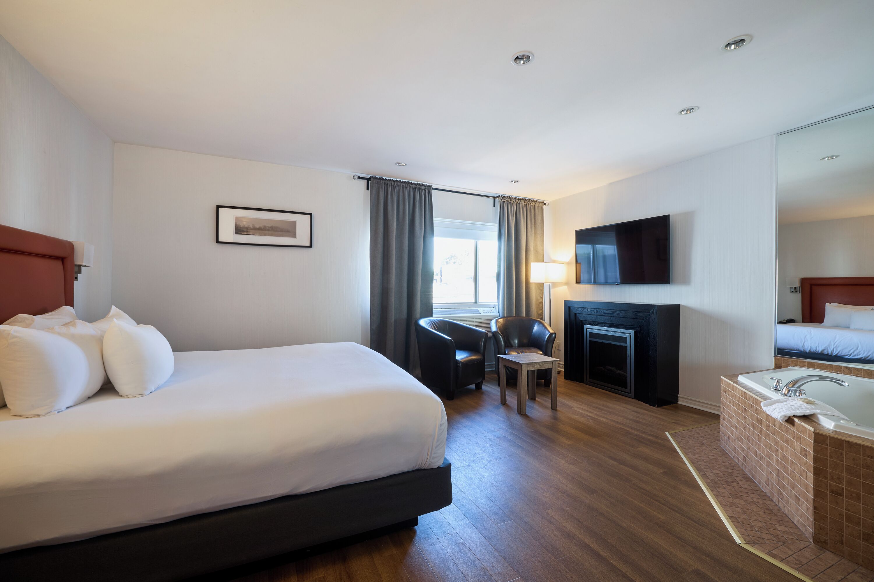 Hotelkamer met een groot bed, een bureau, een stoel, een open haard, een televisie en een badkamer met bad.