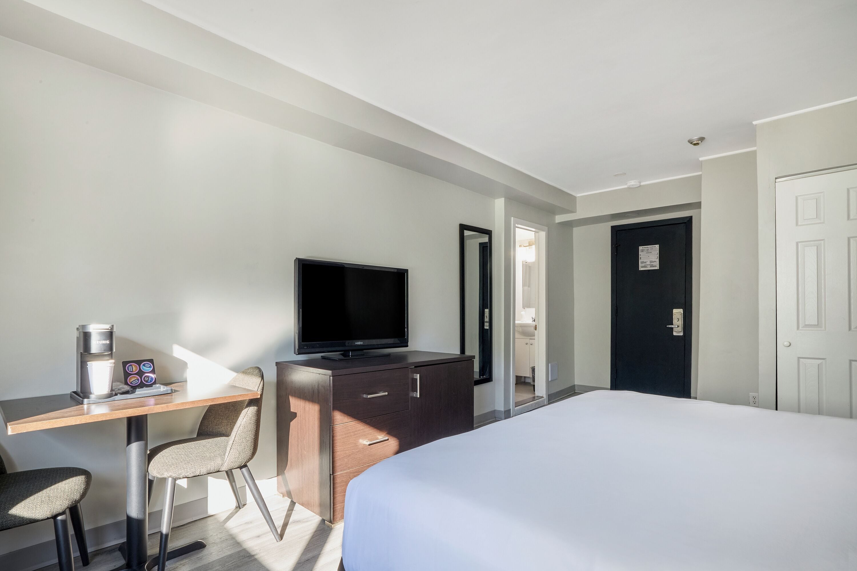 Une chambre d’hôtel comprenant un lit, un bureau avec une machine à café, une télévision et une armoire.
