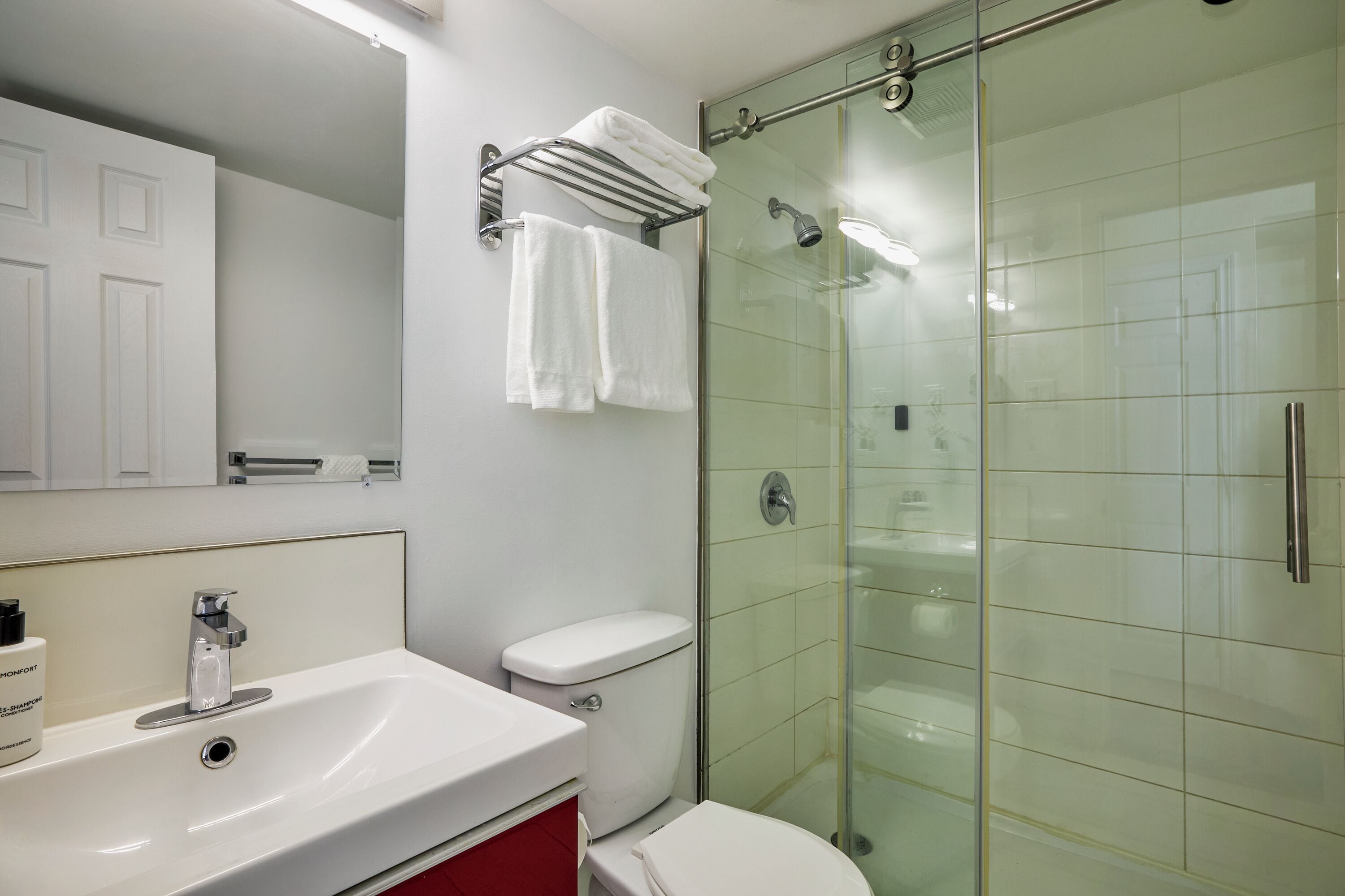 A bathroom with a glass shower enclosure, a white sink, and a toilet.