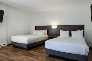 Una habitación de hotel con dos camas, una mesita de noche y una lámpara de pared.