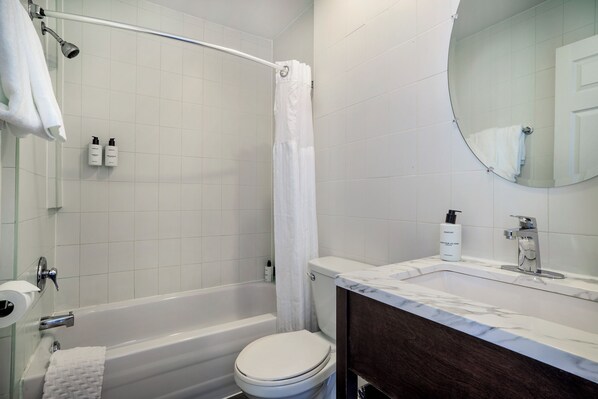 Un baño con bañera, inodoro y lavamanos con espejo.