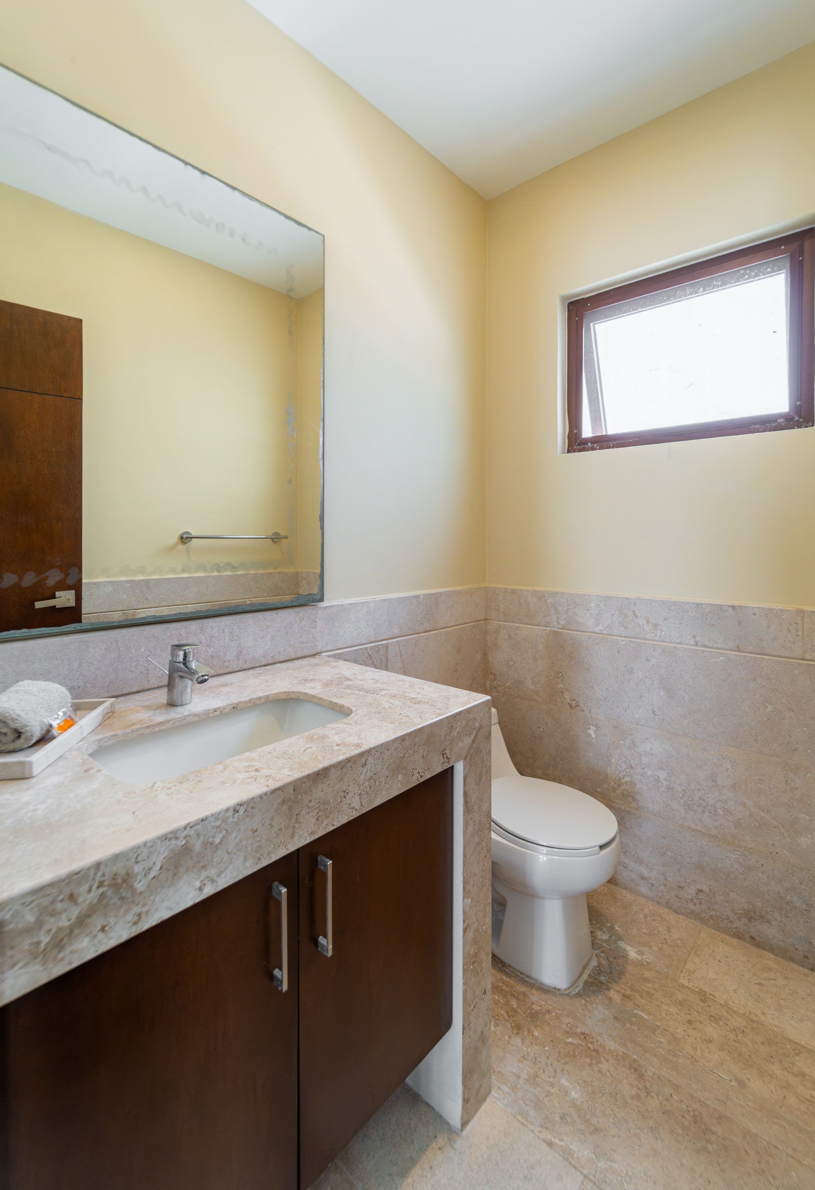 A bathroom with a marble sink, a toilet, and a mirror.