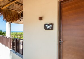 A villa numbered 203 with a wooden door and a balcony with a thatched roof. - Grand Marina Hotel (Telchac Puerto)