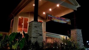 A two-story building with a covered porch, stone pillars, and a banner hanging from the roof.