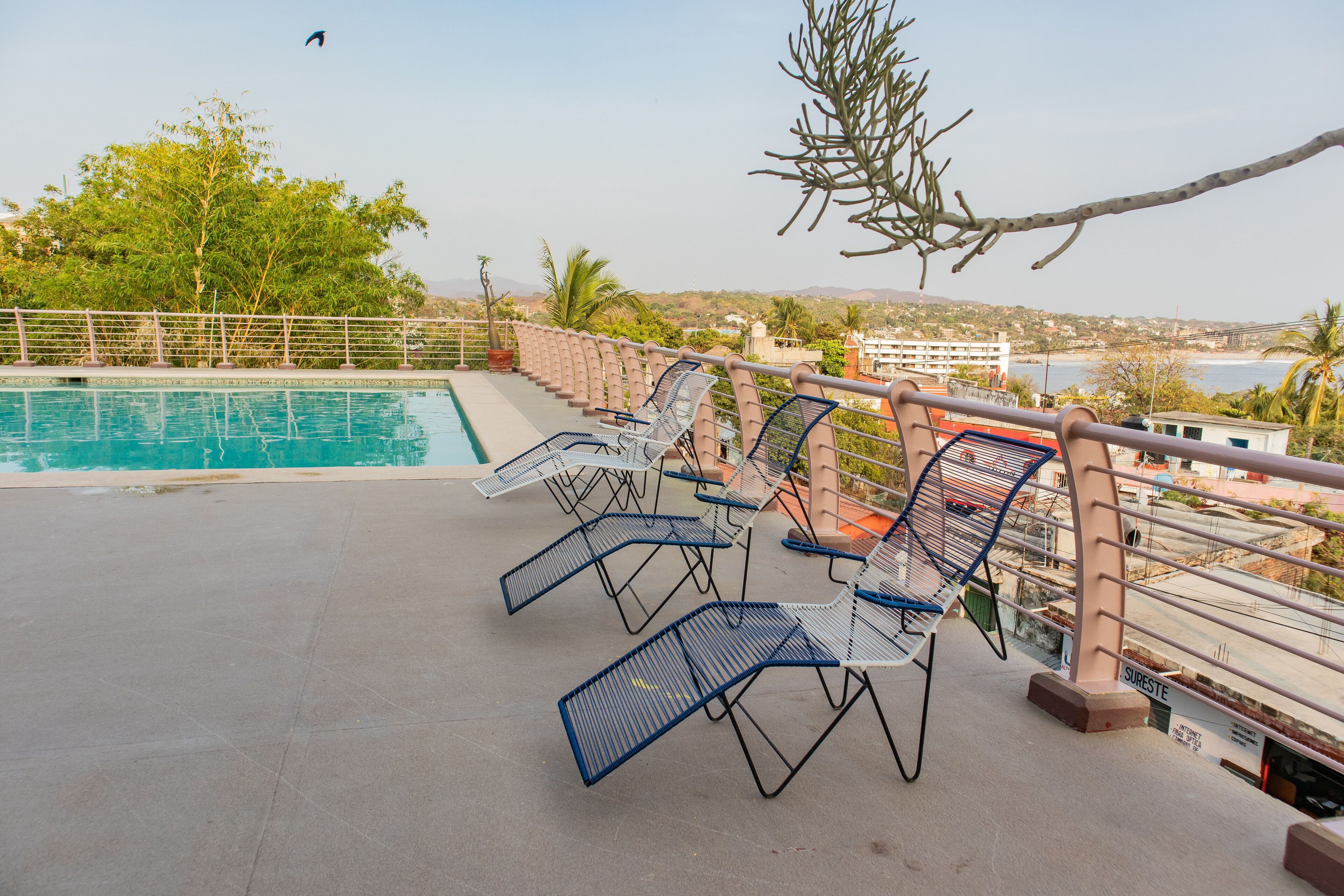 A poolside area with lounge chairs and a view of the sea.