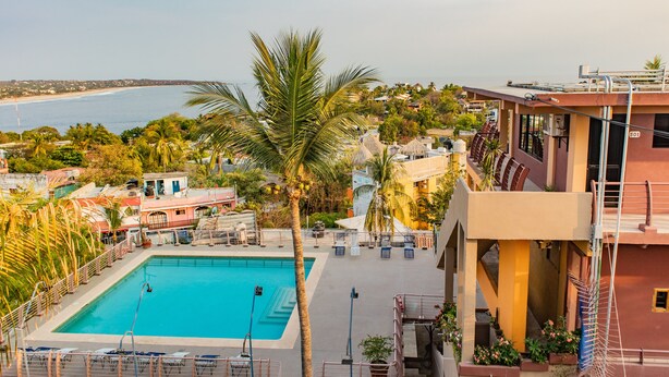 Una piscina con vistas al mar, rodeada de palmeras y edificios.