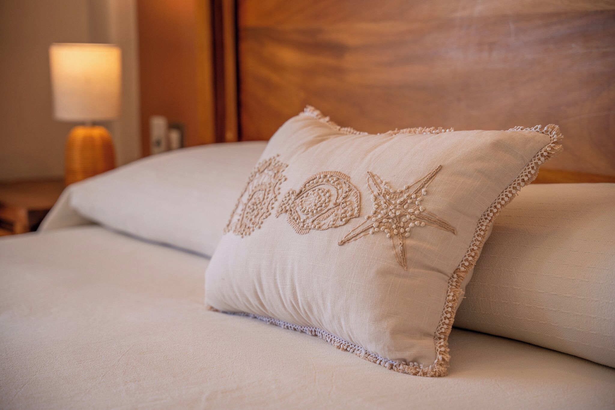 A neatly made bed with a decorative pillow featuring a starfish design.