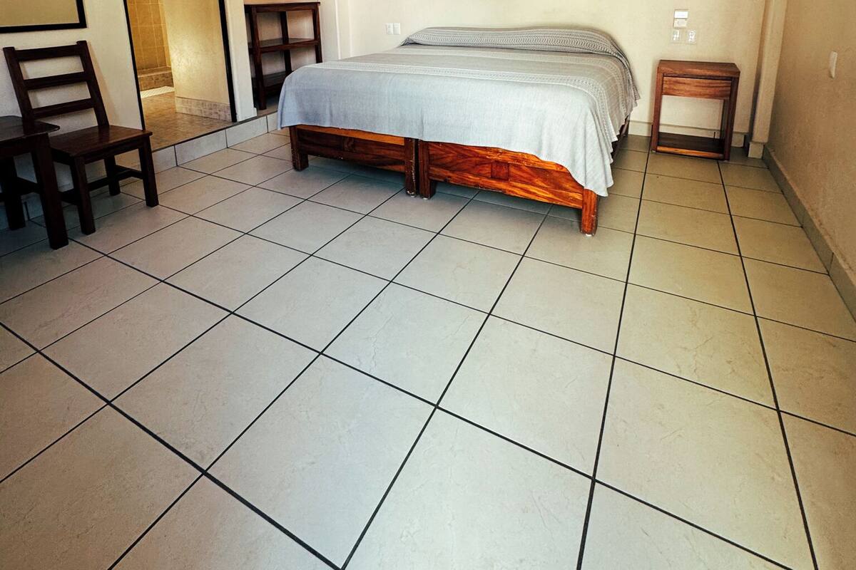 A bedroom with a bed, a ceiling fan, a small table, and a chair.