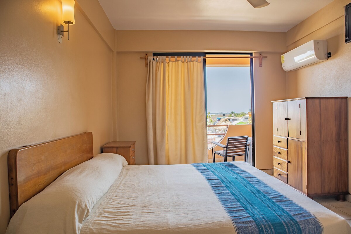 Une chambre d’hôtel avec un lit, une armoire en bois, un bureau et une chaise.