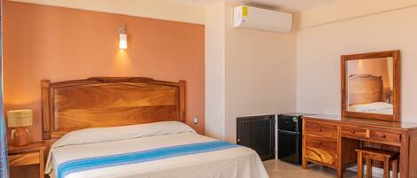 A bedroom with a wooden bed, a desk with a chair, a ceiling fan, and an air conditioning unit.