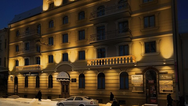 Un hotel de varios pisos con un estilo arquitectónico clásico, que cuenta con balcones y una entrada central con un arco decorativo.